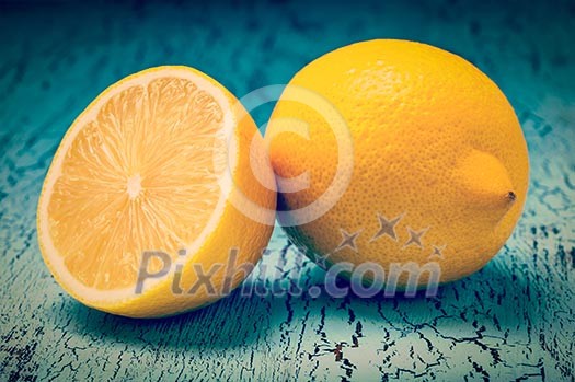 Vintage retro effect filtered hipster style image of lemon and cut half slice on blue wooden background Vintage retro effect filtered hipster style image of lemon and cut half slice on blue wooden background