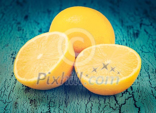 Vintage retro effect filtered hipster style image of lemon and cut half slice on blue wooden background Vintage retro effect filtered hipster style image of lemon and cut half slice on blue wooden background
