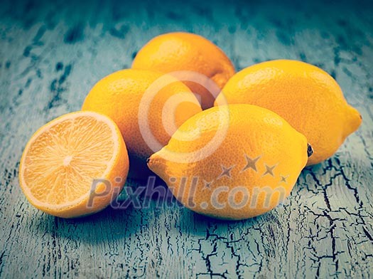 Vintage retro effect filtered hipster style image of five fresh ripe yellow lemons on blue wooden background
