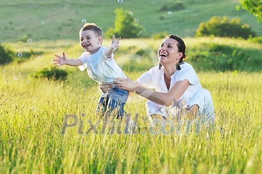 happy child and woman outdoor playing with soap bubble on meadow happy child and woman outdoor playing with soap bubble on meadow