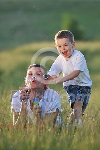 happy child and woman outdoor playing with soap bubble on meadow happy child and woman outdoor playing with soap bubble on meadow