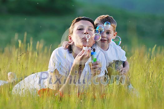 happy child and woman outdoor playing with soap bubble on meadow happy child and woman outdoor playing with soap bubble on meadow