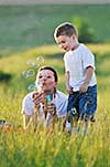 happy child and woman outdoor playing with soap bubble on meadow