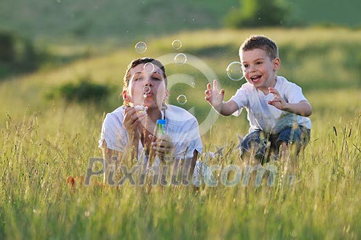 happy child and woman outdoor playing with soap bubble on meadow happy child and woman outdoor playing with soap bubble on meadow