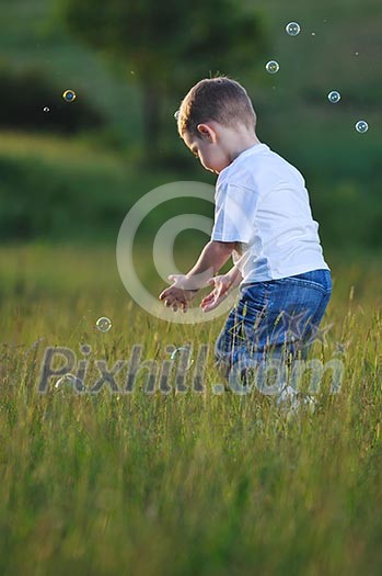 happy young beautiful child have fun on eadow with soap bubbles toy