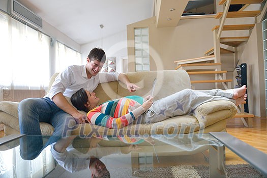 pregnant woman with her husband have fun relax and using tablet comture at modern home