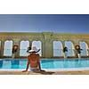 Happy smiling woman with hat and sunglasses  in swimming pool at tropical resort