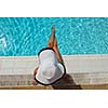 Happy smiling woman with hat and sunglasses  in swimming pool at tropical resort