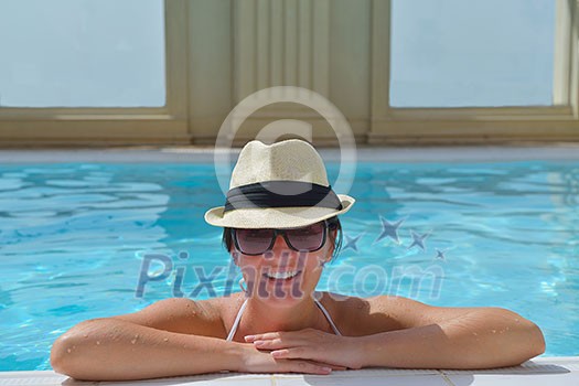 Happy smiling woman with hat and sunglasses in swimming pool at tropical resort Happy smiling woman with hat and sunglasses in swimming pool at tropical resort