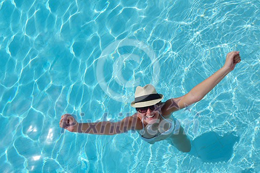 Happy smiling woman with hat and sunglasses in swimming pool at tropical resort Happy smiling woman with hat and sunglasses in swimming pool at tropical resort