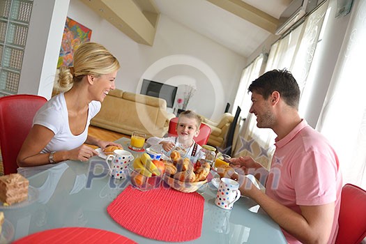 happy young family have healthy breakfast at kitchen with red details on bright morning light