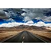 Travel forward concept background - road on plains in Himalayas with mountains and dramatic clouds. Manali-Leh road, Ladakh, Jammu and Kashmir, India