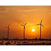 Green renewable energy concept - wind generator turbines sihouettes on sunset