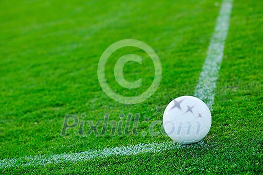 white Soccer ball on grass at goal and stadium in background white Soccer ball on grass at goal and stadium in background