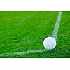 white Soccer ball on grass at goal and stadium in background