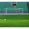 white Soccer ball on grass at goal and stadium in background