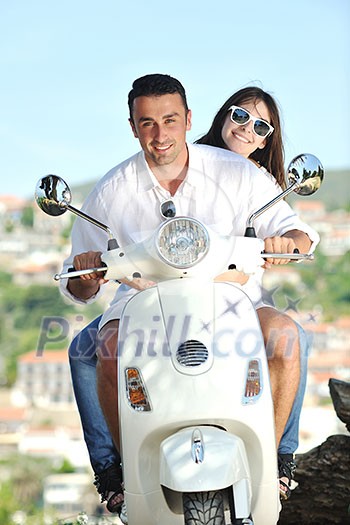 Portrait of happy young love couple on scooter enjoying themselves in a park at summer time Portrait of happy young love couple on scooter enjoying themselves in a park at summer time