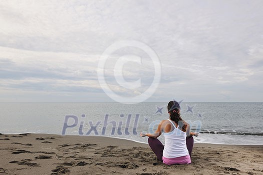 young woman meditating yoga in lotus positin on the beach at early morning young woman meditating yoga in lotus positin on the beach at early morning