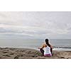 young woman meditating yoga in lotus positin on the beach at early morning