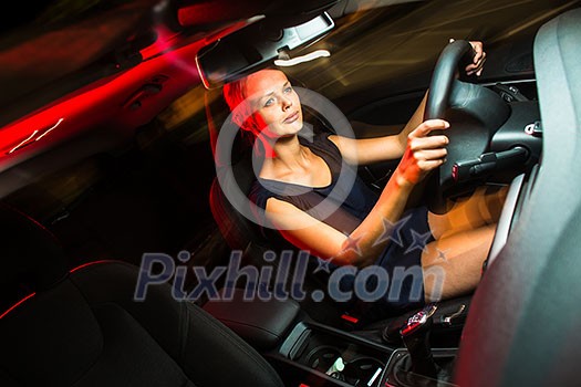 Driving a car at night - pretty, young woman driving her modern car at night, in a city (shallow DOF; color toned image) Driving a car at night - pretty, young woman driving her modern car at night, in a city (shallow DOF; color toned image)