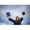 Pretty, young woman celebrating joyfully her graduation - spreading wide her arms, holding her diploma, savouring her success (color toned image; shallow DOF)