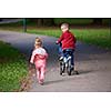 happy kids in park, boy and girl in nature with bicycle have fun