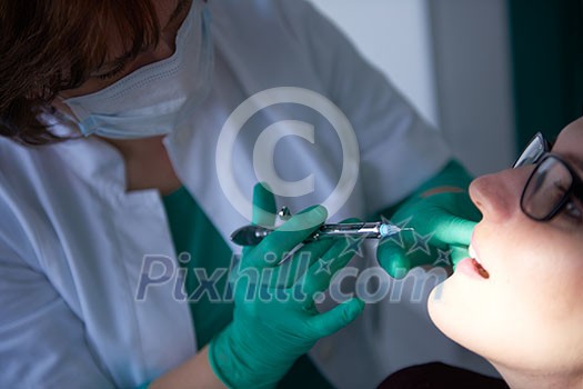 Closeup of a woman patient at the dentist waiting to be checked up with the woman doctor in the background Closeup of a woman patient at the dentist waiting to be checked up with the woman doctor in the background