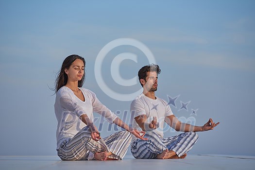 young couple practicing yoga at sunset in modern home terace with ocean and sunset in background young couple practicing yoga at sunset in modern home terace with ocean and sunset in background