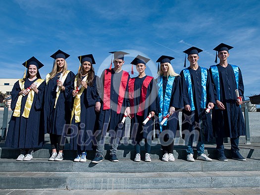 young graduates students group standing in front of university building on graduation day young graduates students group standing in front of university building on graduation day