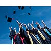 high school students graduates tossing up hats over blue sky.