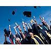 high school students graduates tossing up hats over blue sky.