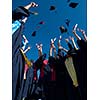 high school students graduates tossing up hats over blue sky.