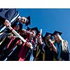 high school students graduates tossing up hats over blue sky.