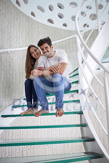 relaxed young couple on spiral glass stairs in modern home villa indoors relaxed young couple on spiral glass stairs in modern home villa indoors