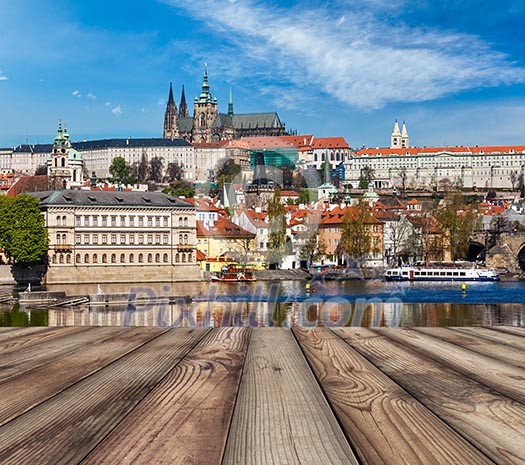 Wooden planks vith view of Prague Charles bridge over Vltava river and Gradchany (Prague Castle) and St. Vitus Cathedral in background