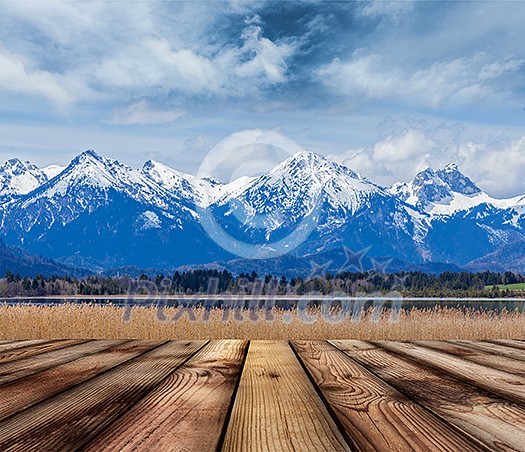 Wooden planks floor with Bavarian Alps countryside lake landscape in background. Bavaria, Germany
