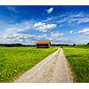 Rural road in summer meadow with wooden shed. Bavaria, Germany