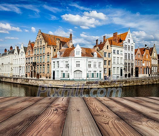 Wooden planks with European view of Bruges canal and old historic houses of medieval architecture in background. Brugge, Belgium Wooden planks with European view of Bruges canal and old historic houses of medieval architecture in background. Brugge, Belgium