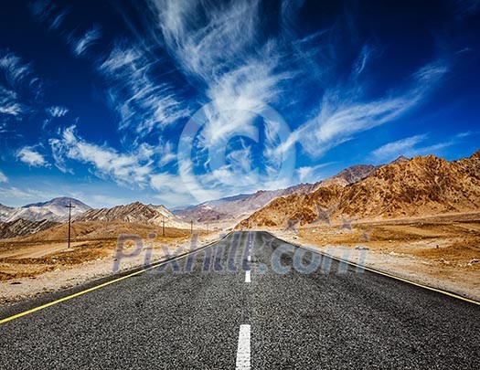 Travel forward concept background - road in mountains Himalayas with dramatic clouds on blue sky. Ladakh, Jammu and Kashmir, India