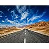 Travel forward concept background - road in mountains Himalayas with dramatic clouds on blue sky. Ladakh, Jammu and Kashmir, India