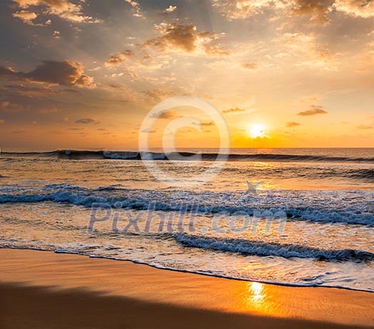 Sunrise with rising sun on morning beach