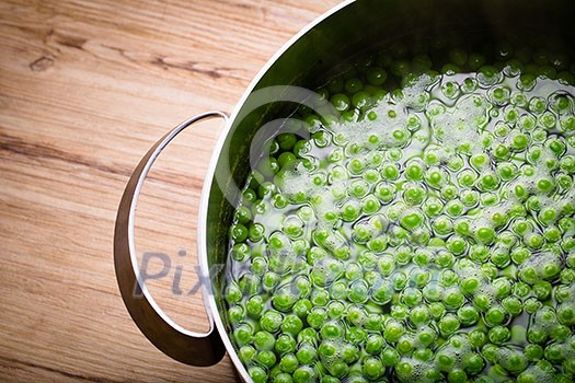 Green peas in a pot on a wooden table Green peas in a pot on a wooden table