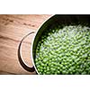 Green peas in a pot on a wooden table