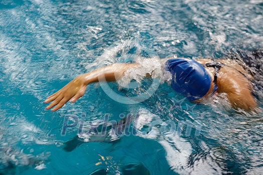 Female swimmer in an indoor swimming pool - doing crawl (shallow DOF) Female swimmer in an indoor swimming pool - doing crawl (shallow DOF)