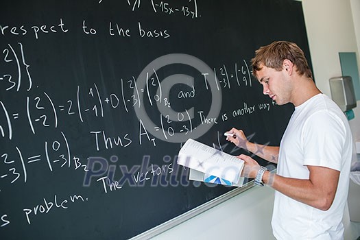 Handsome college student solving a math problem during math class in front of the blackboard/chalkboard (color toned image) Handsome college student solving a math problem during math class in front of the blackboard/chalkboard (color toned image)