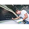 Handsome college student solving a math problem during math class in front of the blackboard/chalkboard (color toned image)