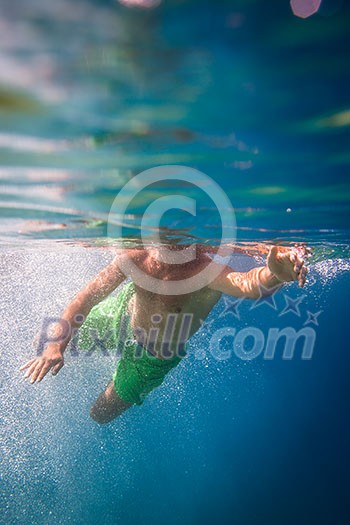 Underwater shot of male swimmer in green shorts Underwater shot of male swimmer in green shorts