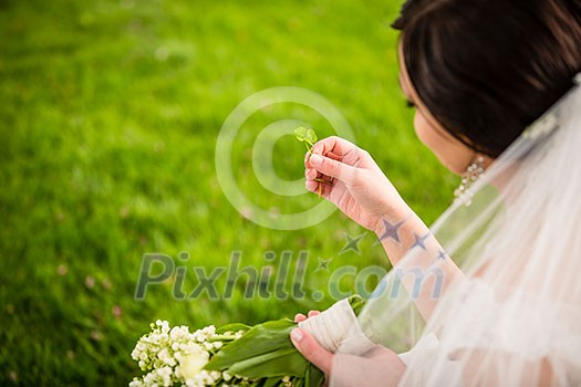 Bride on her wedding day with lucky fortune clover she has just found