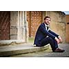 Handsome groom on his wedding day waiting for his bride in front of a church