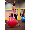 Group people in a pilates class at the gym - young woman with gymball at fitness training (shallow DOF, color toned image)